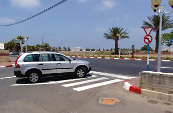 צומת עירוני עם מעבר חצייה רחב, כביש מתרחב, ללא תמרור זכות קדימה נראה בבירור בתמונה.