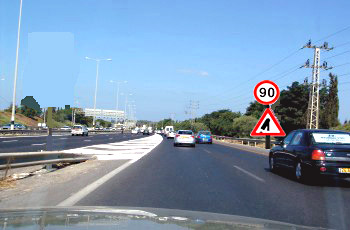 כביש בין-עירוני עם תמרור מהירות מוגבלת 90 ותמרור אזהרה משולש למיזוג תנועה.