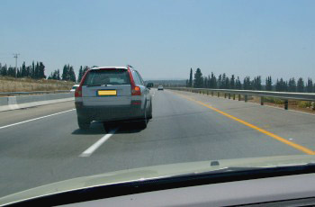 כביש דו-נתיבי: רכב כסוף בנתיב השמאלי קרוב לרכב שלך, מתכונן לחזור לנתיב הימני.