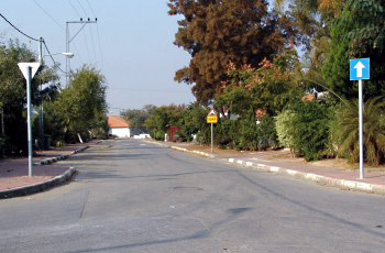 רחוב שקט עם תמרור "תן זכות קדימה" משמאל ותמרור כביש חד-סטרי כחול מימין.