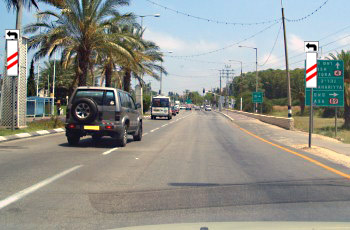 שלטים מלבניים לבנים עם חץ שחור מתעקל שמאלה, מותקנים מעל לוחות פסים אלכסוניים אדום-לבן, בשני צדי הכביש.