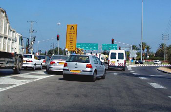 רכבים עומדים בתוך שטח הפרדה בין נתיבים, ליד תמרור אין פנייה פרסה.