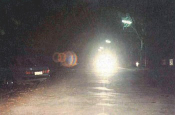 נסיעה לילית עם אורות רכב ממול מסנוורים ורכב חונה בצד הכביש.