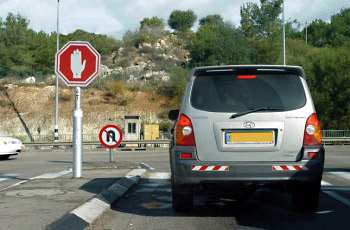 תמרור עצור משולב עם תמרור איסור פנייה בצומת, רכב כסוף חונה סמוך לתמרורים